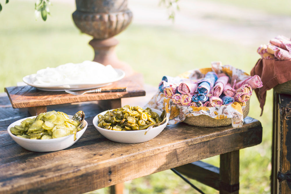 Wooden Table with Pickles and Pink, Blue Napkins Outdoors