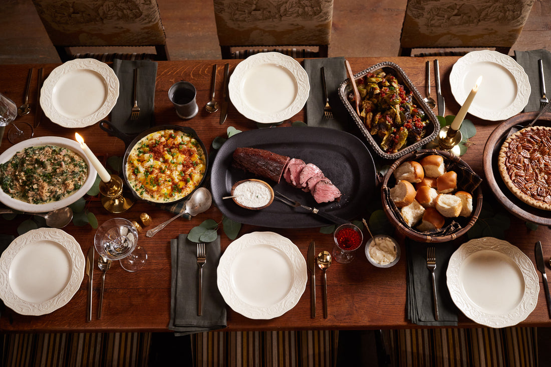 A holiday feast from Goode Co with a beautiful cut of bbq in the center plate and sides like rolls.