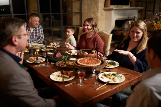 Family and friends gathered around a holiday table enjoying Goode Co. BBQ food.
