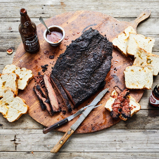 Classic Mesquite Smoked Brisket on Wooden Cutting Board with Goode Co. BQ Sauce