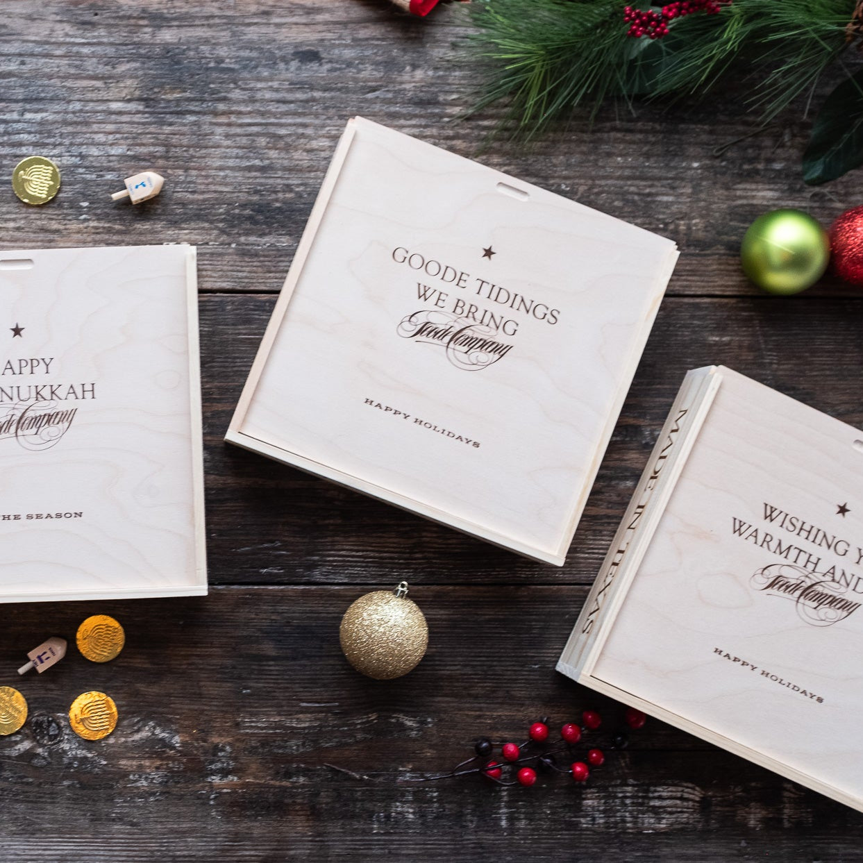 Four holiday-themed wood gift boxes on a wooden surface with decorative elements.