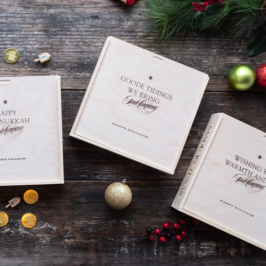 Four holiday-themed wood gift boxes on a wooden surface with decorative elements.